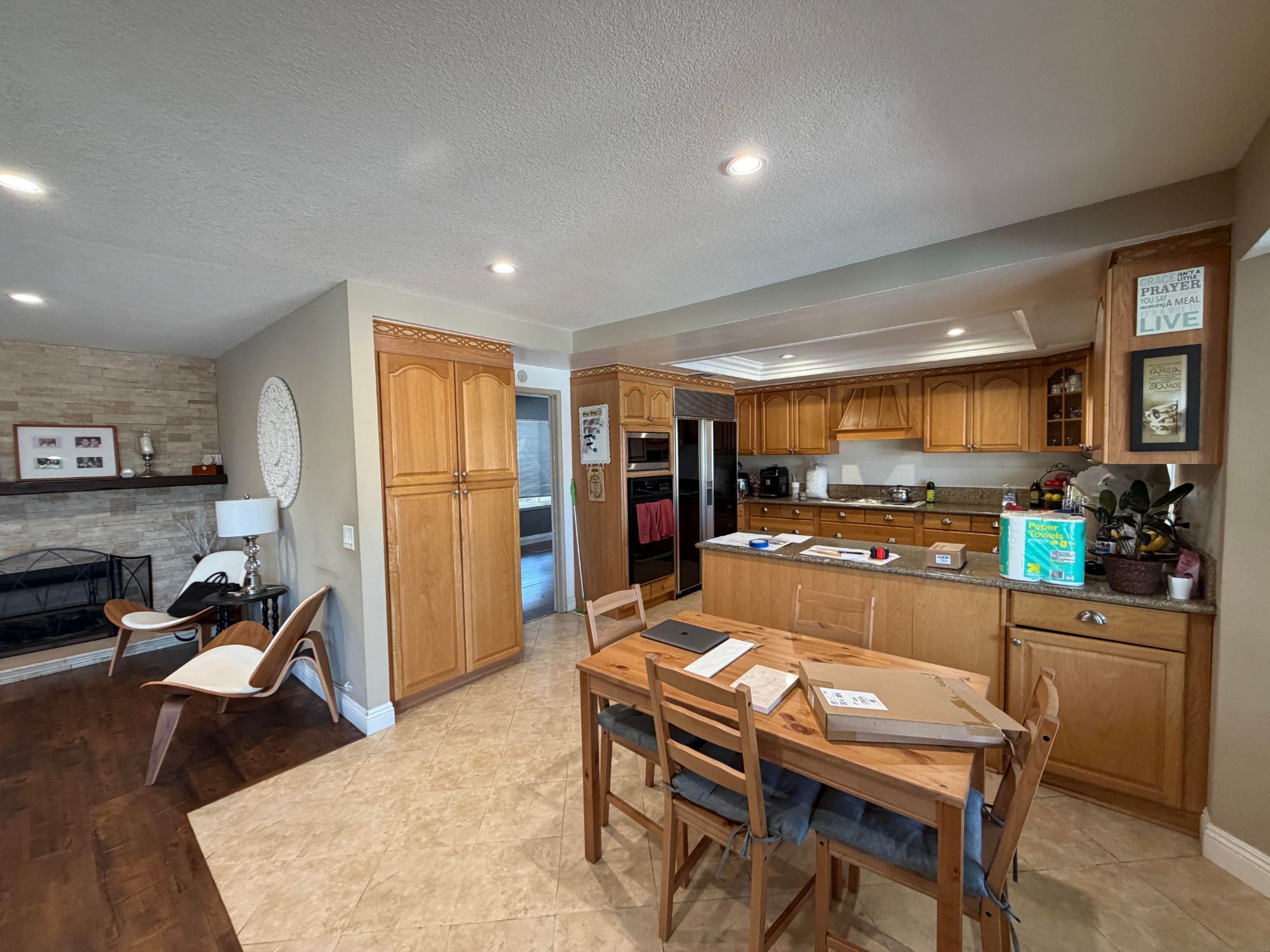 Before: dated oak kitchen with granite counters, tile floor and a closed-off peninsula next to the family room