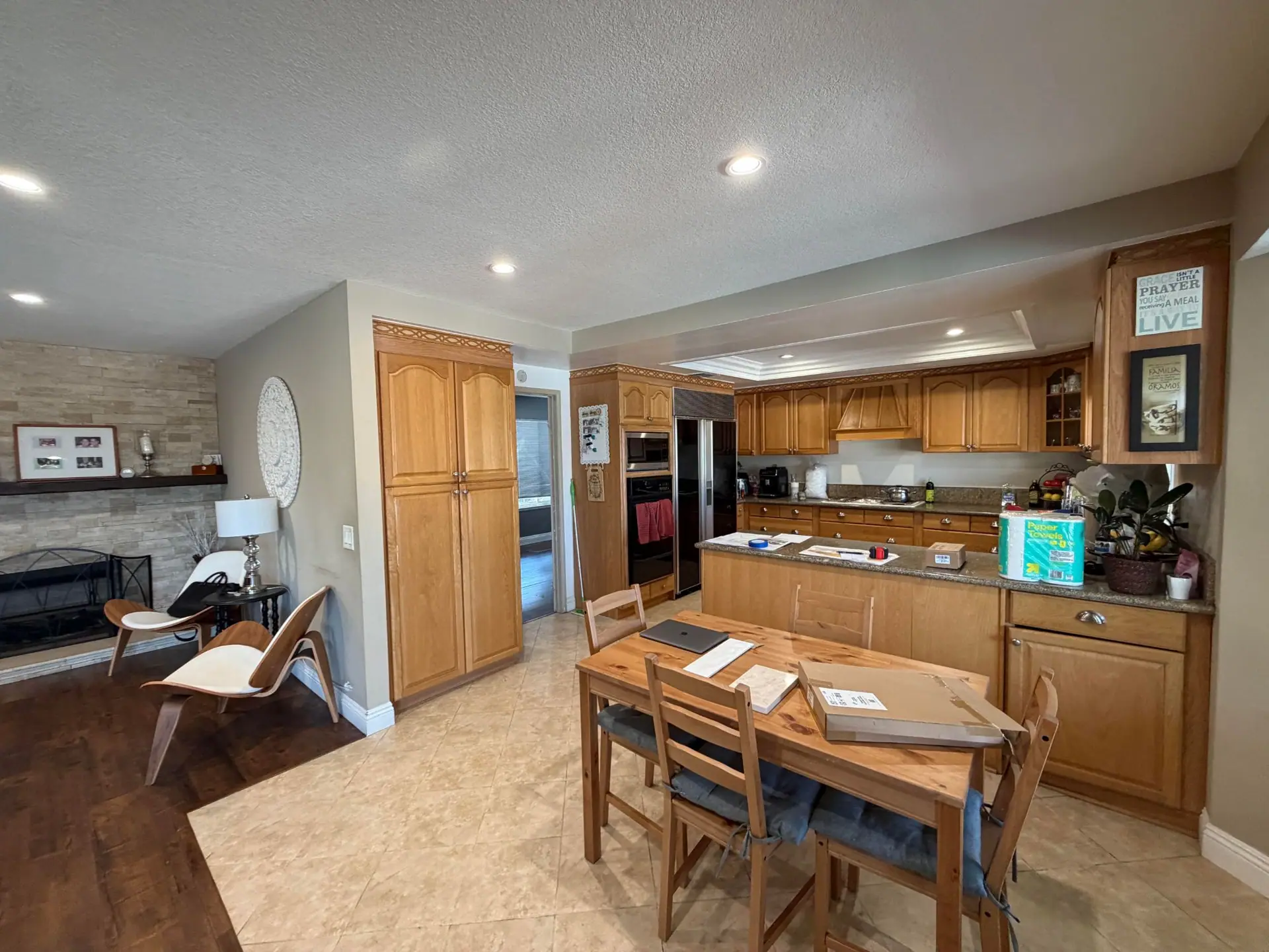 Before: dated oak kitchen with granite counters, tile floor and a closed-off peninsula next to the family room
